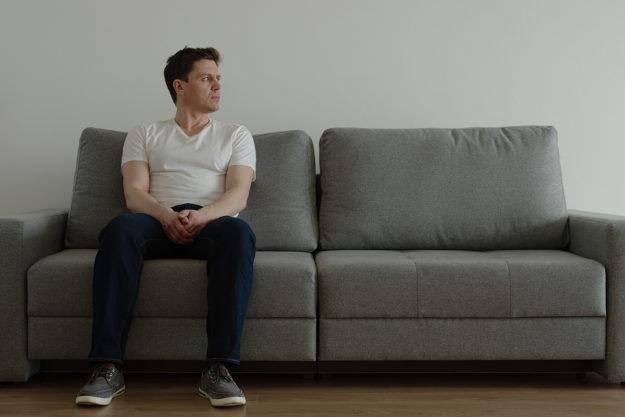 signs of opiate addiction (1) man on couch thinking about signs of opiate addiction